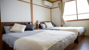 A hotel room with two beds, a wooden ceiling, an air conditioning unit, and a window with curtains. - BIEI RELAX STAY A (Biei)