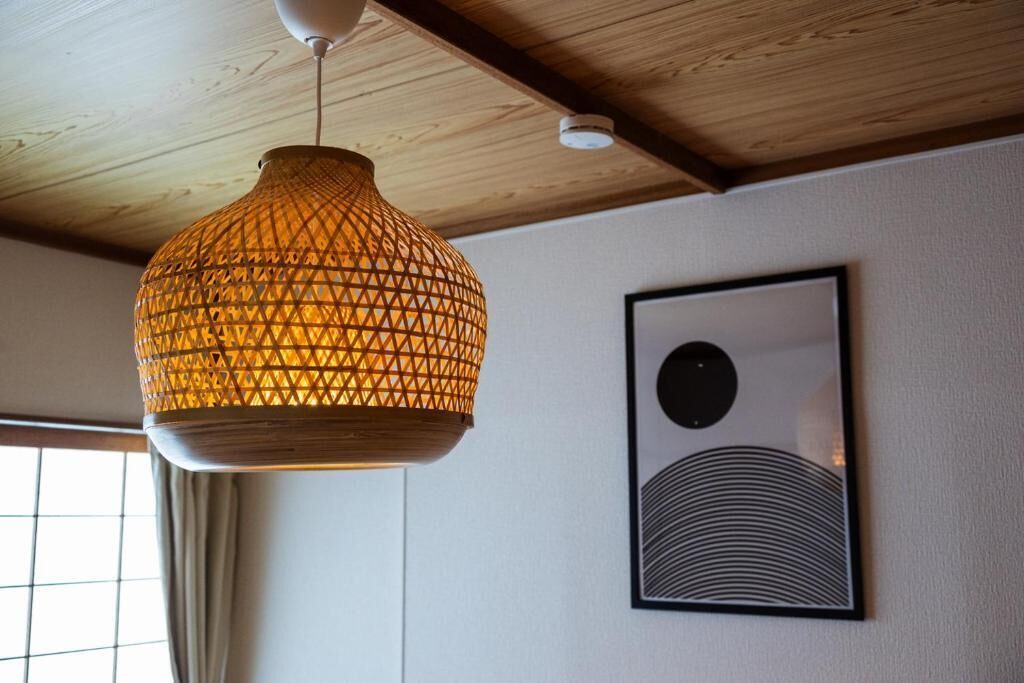 Eine Pendelleuchte mit geometrischem Muster, ein gerahmtes abstraktes Kunstwerk an der Wand und eine Holzbalkendecke.