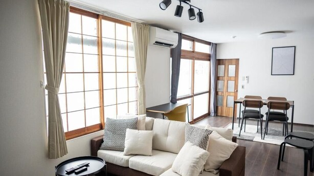 A living room with a sofa, a small table, and a dining area with chairs. - BIEI RELAX STAY A (Biei)