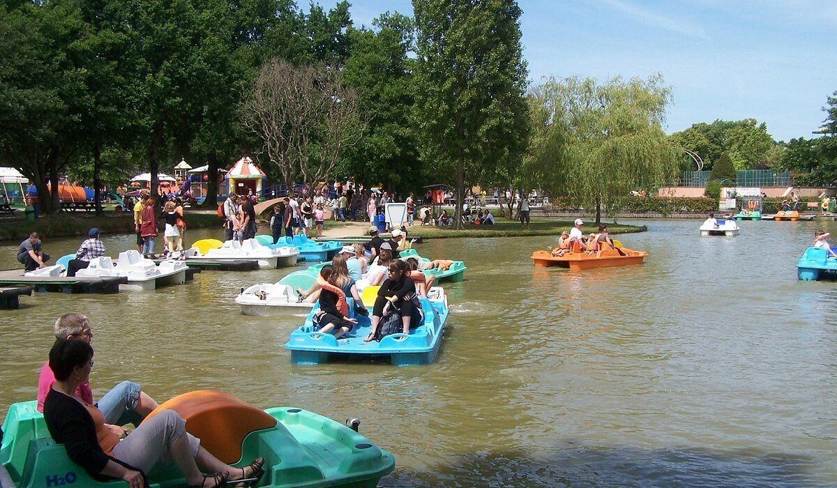 Een groep mensen op waterfietsen in een park met bomen en een prieel op de achtergrond.