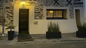 Un edificio moderno con fachada de piedra, una puerta negra y dos ventanas.