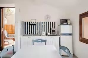 A room with a white table, two chairs, a small TV on a white cabinet, and a window with a view of the outdoors. - Luxurious Holiday House With Private Pool in Costa Paradiso (Trinità d'Agultu e Vignola)