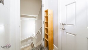 A hallway with white doors, a wooden shelf unit, and a carpeted floor.
