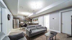 A modern living room with a grey sofa, a small table, and a kitchen in the background.
