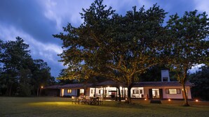 A two-story house with a patio area and a large tree in front. - Villa Wild Ceylon by TSC (NW)