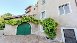 A building with a green door, a balcony, and a cobblestone courtyard.
