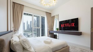 Ein modernes Hotelzimmer mit einem großen Bett, einem an der Wand montierten Fernseher und Blick auf die Stadt.