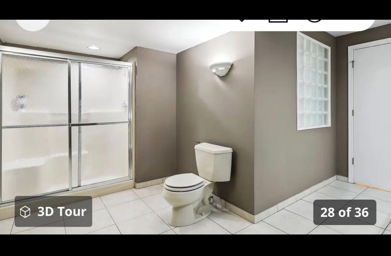 A bathroom with a toilet, a glass shower enclosure, and a window.