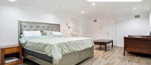 Une chambre à coucher avec un lit, des tables de chevet, une commode et une porte.