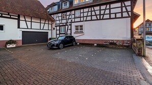 Une maison traditionnelle à colombages, avec une voiture garée dans l’allée.