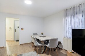 A dining area with a table, chairs, a television, and a radiator.