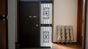 Une porte en bois ornée d’un portail en métal décoratif, un banc avec des coussins et un porte-chaussures contenant plusieurs paires de chaussures.