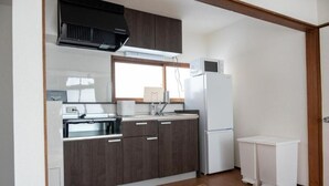 Une cuisine de taille réduite, avec des meubles de couleur bois foncé, un réfrigérateur blanc et un four à micro-ondes.