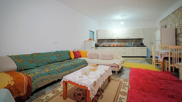 A living room with a sofa, a coffee table, and a dining area with chairs and a table. - Dreamy Farm (Mesopotam)