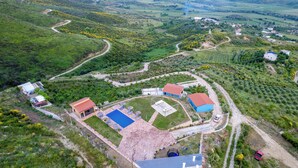 An aerial view of a rural property with a swimming pool, multiple buildings, and winding roads. - Dreamy Farm (Mesopotam)