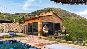 A wooden cabin with a pool, outdoor seating, and a view of a green hillside. - Dreamy Farm (Mesopotam)