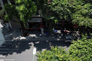 Une vue de rue avec un café appelé « HAT NGUAN » et une voiture garée.
