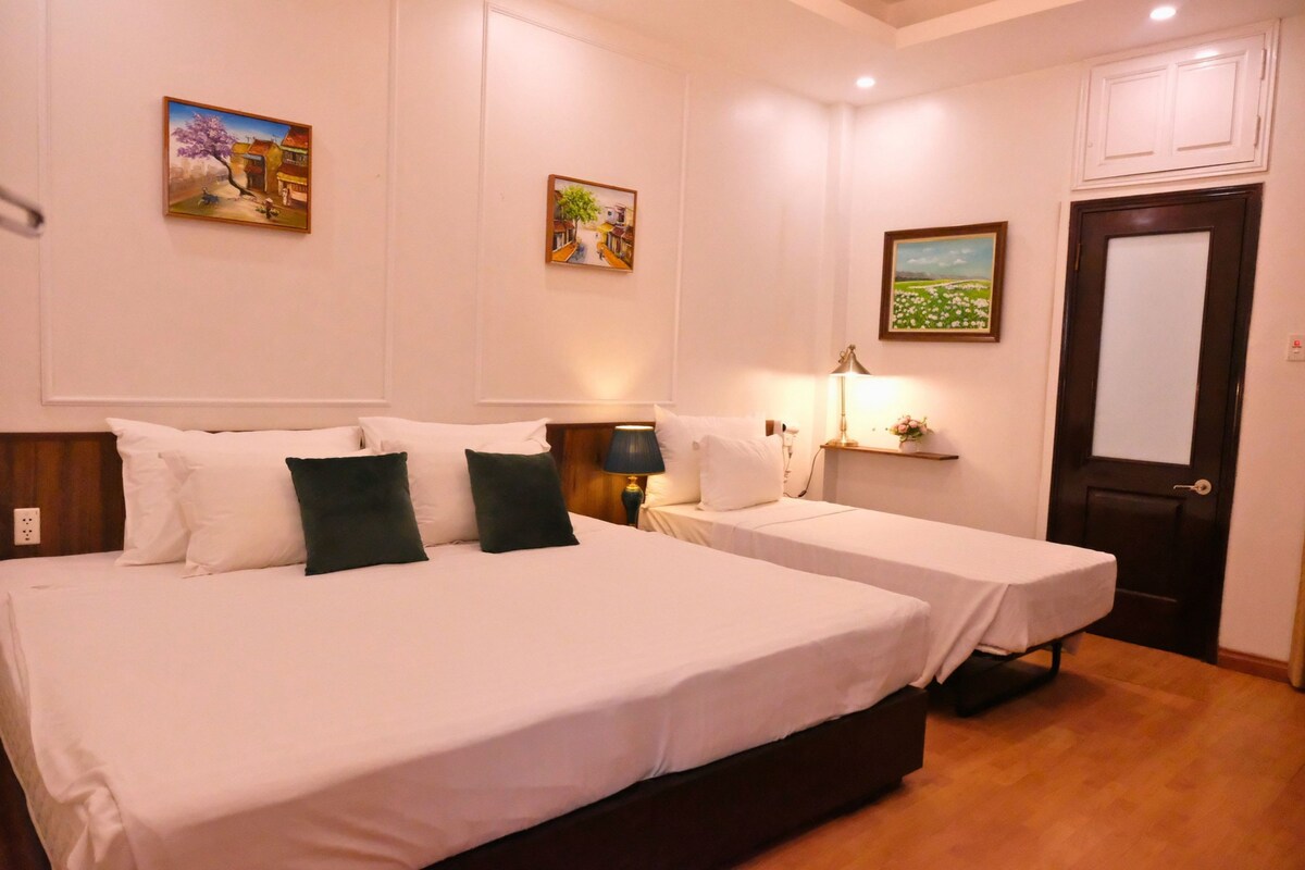 Une chambre d’hôtel avec deux lits, une table de chevet, une lampe et une porte.