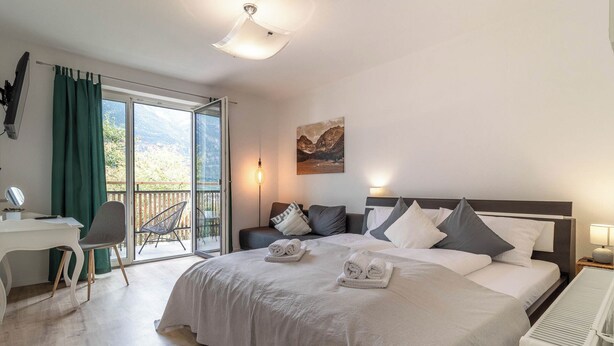 Une chambre d’hôtel équipée d’un lit, d’un bureau, d’une chaise, d’un radiateur et offrant une vue sur l’extérieur.