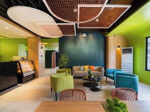 A modern lounge area with a sofa set, chairs, a coffee station, and a large window. - Bayfront CoLive+ (Cebu City)