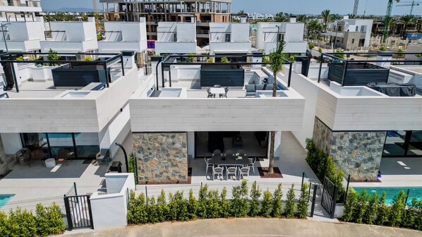 A modern residential building with multiple balconies, a stone facade, and a pool area.