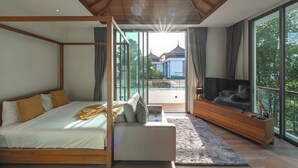 A bedroom with a four-poster bed, a sofa, a TV, and large windows offering a view of the outside. - Pool Villa Near Beach Boat Avenue V219 (Choeng Thale)