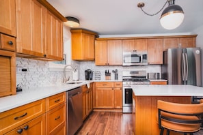 Una cocina moderna con armarios de madera, electrodomésticos de acero inoxidable y encimera blanca.