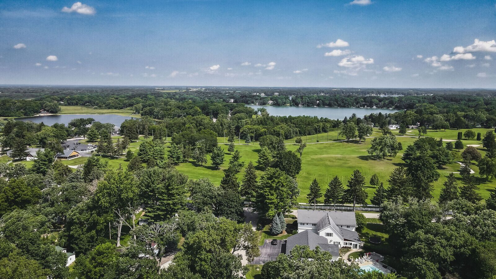 Ein Luftbild eines Wohngebiets mit Häusern, einem Golfplatz und einem See.