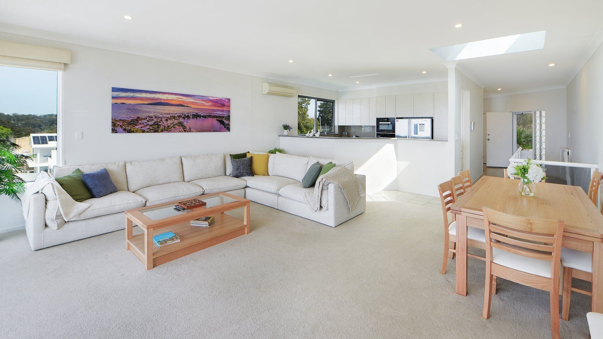 A modern living room with a sofa, coffee table, and dining area.