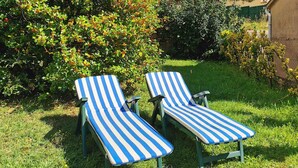 Dos sillones a rayas en un jardín cubierto de césped.