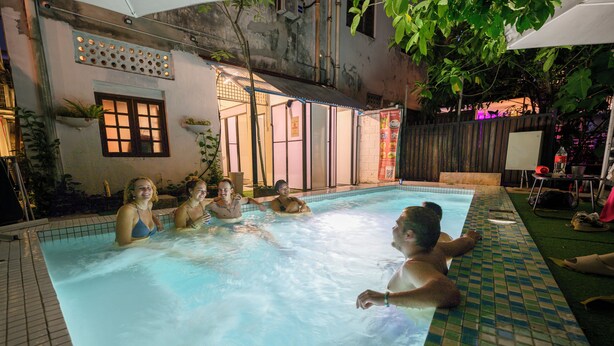 A swimming pool area with tiled flooring, a window with a view, and a door leading to an adjacent building. - Poolside By Mingle (Kuala Lumpur)