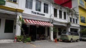 A building with a sign reading "THE MANOR" and a red and white striped awning indicating breakfast, lunch, and dinner services. - Poolside By Mingle (Kuala Lumpur)