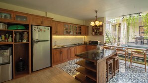Une cuisine dotée de meubles en bois, d’un réfrigérateur, d’un four à micro-ondes et d’un coin repas avec une table et des chaises.