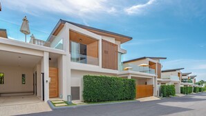 A modern residential building with a flat roof, large windows, and a well-maintained hedge. - Near Beach & Famous Boat Ave V217 (Choeng Thale)