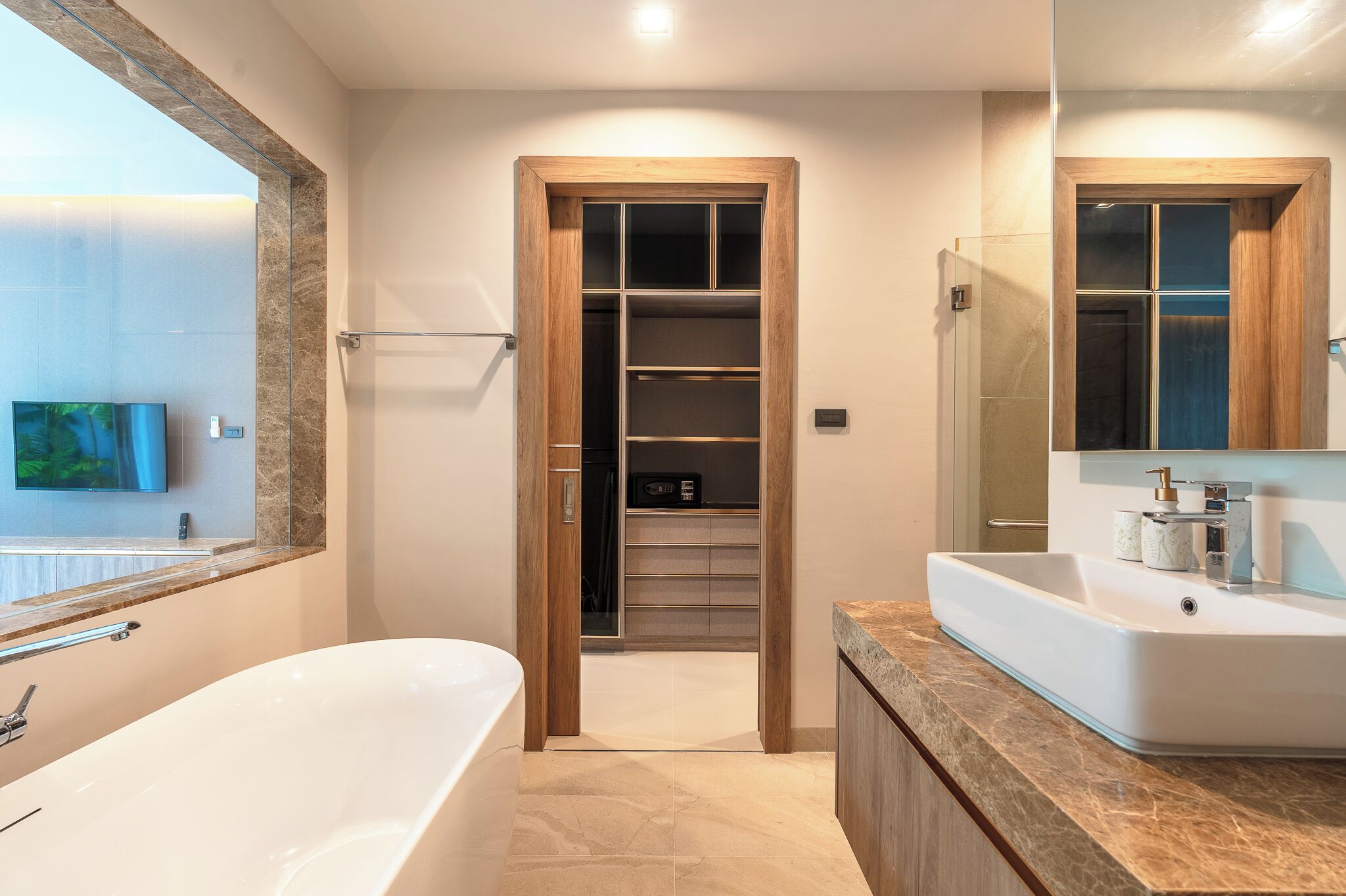 A modern bathroom with a bathtub, a vanity with a sink, and a walk-in closet with shelves.