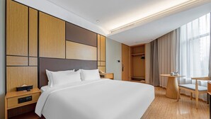 A modern hotel room with a large bed, wooden headboard, bedside tables, a small round table with a chair, and a walk-in closet. - JI Hotel -Shanghai Changshou Road (Shanghai)