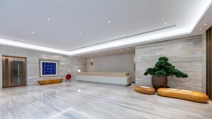A modern reception area with a marble floor, a reception desk, a large potted plant, and a red chair. - JI Hotel -Shanghai Changshou Road (Shanghai)