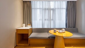 A compact room with a sofa, a small table, a nightstand, and a window with curtains. - JI Hotel -Shanghai Changshou Road (Shanghai)
