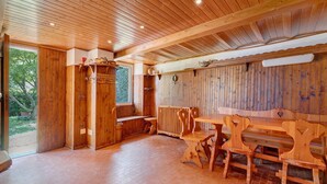Interior de madera con una banca y una mesa, paredes de madera y una ventana.