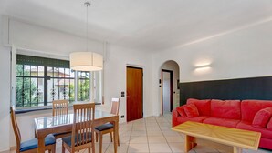Un comedor con una mesa, sillas, un sofá rojo y un banco de madera.
