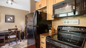 Una cocina con un refrigerador negro, armarios de madera, un microondas y una estufa.