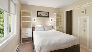 Un dormitorio con una cama, mesita de noche, cómoda, ventana y puerta.
