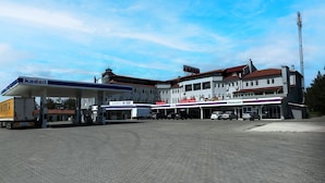 Um posto de combustível com placa Kadoil, um supermercado Carrefour, um hotel e um hotel Novo Star.