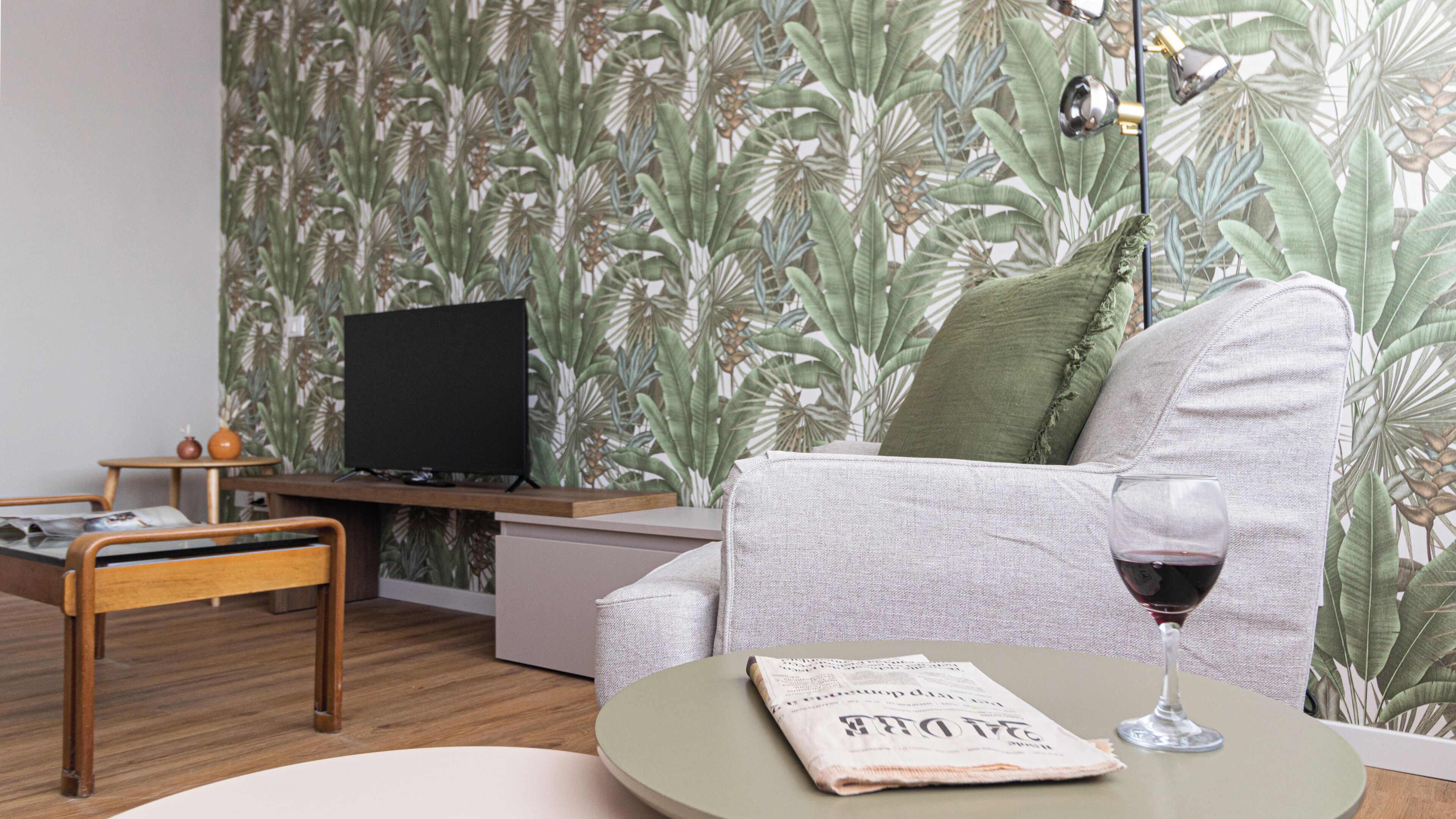 A living room with a sofa, a coffee table with a newspaper, a television on a stand, and a lamp.