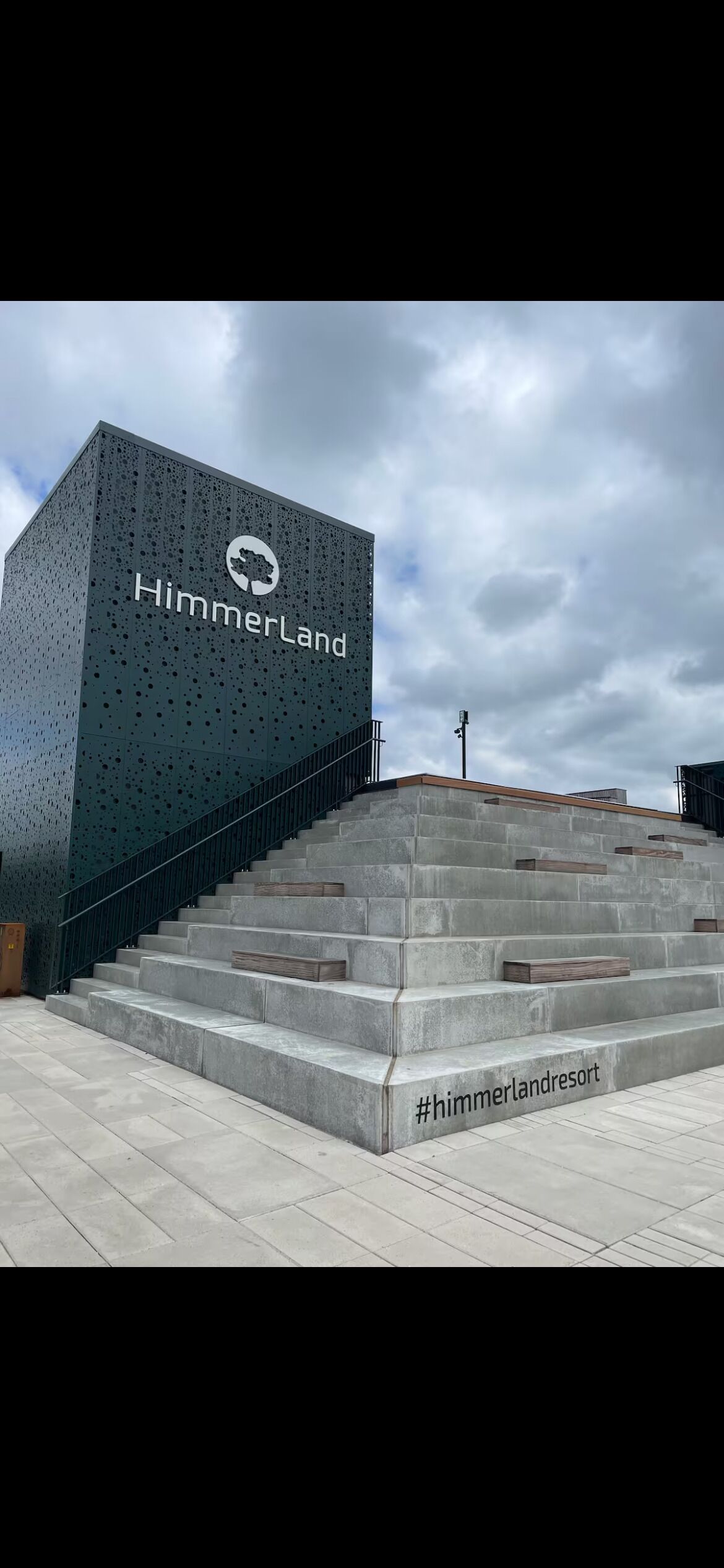 Ein modernes Gebäude mit der Aufschrift 'HimmerLand' auf der Fassade, inklusive Logo und einer Treppe zum Eingang.