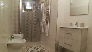 Un baño con inodoro, lavamanos, ducha y toallero.