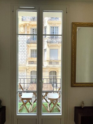 A room with a large window, a wooden table, and a chair.