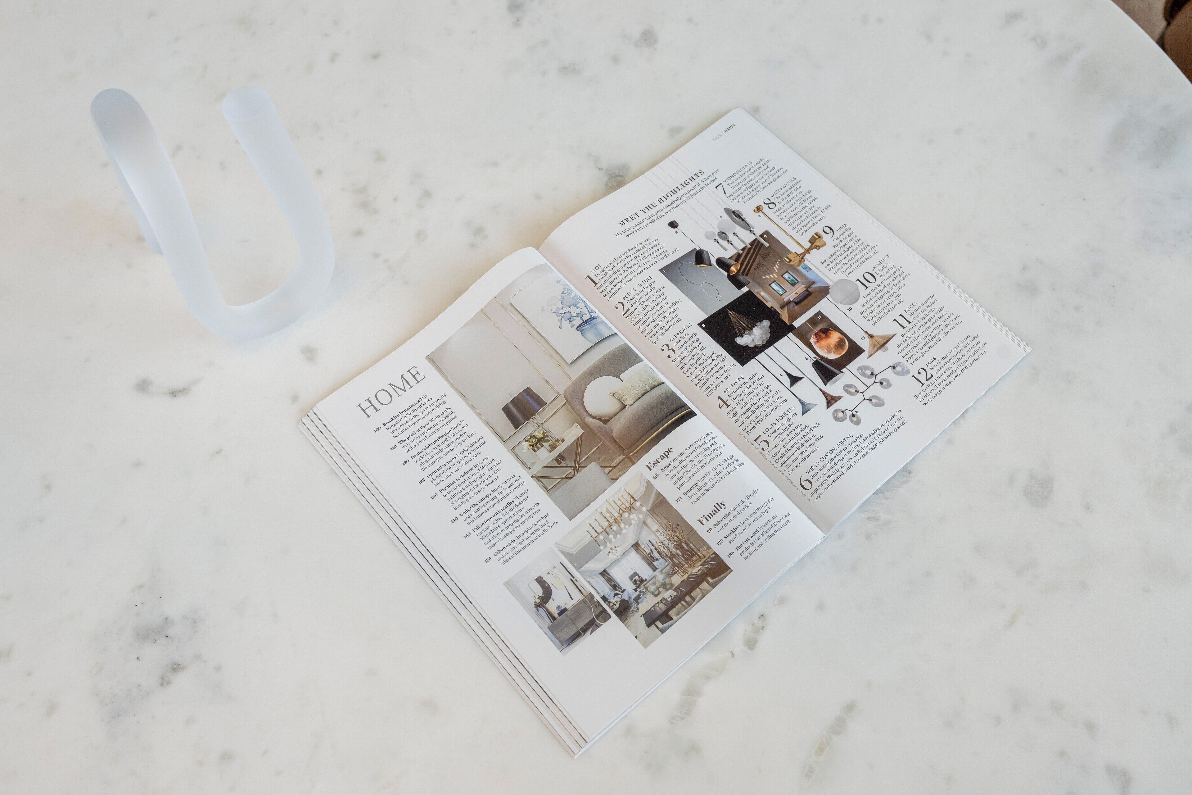 Eine Magazineseite mit Innenarchitektur-Beiträgen, darunter ein Abschnitt mit der Überschrift 'MEET THE HIGHLIGHTS', der Fotos von Beleuchtungskörpern und Dekorationen zeigt.