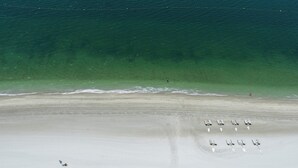 Vista aérea de una playa con filas de tumbonas y algunas personas.