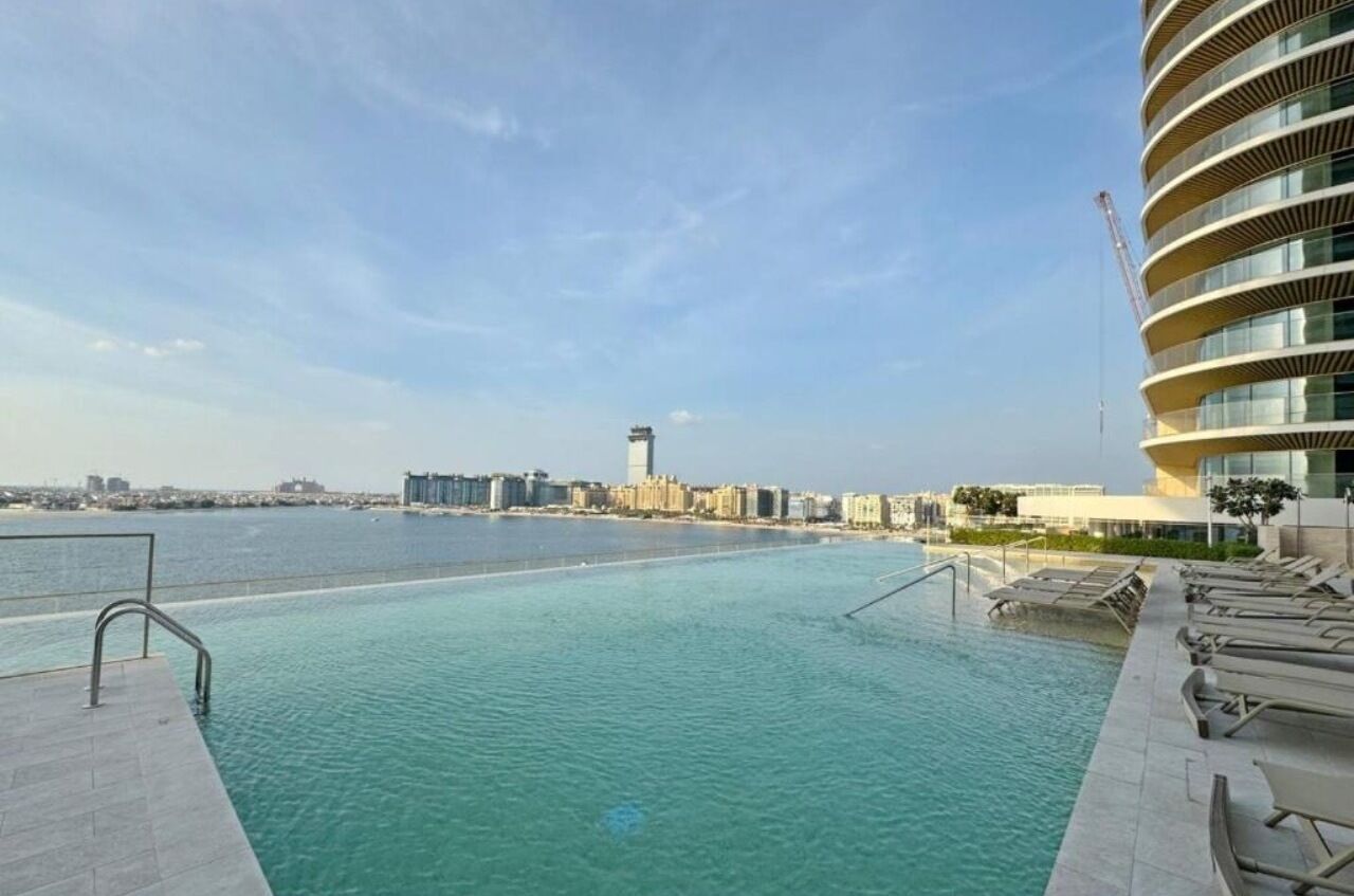 A swimming pool with a view of a city skyline and a modern building with a curved facade.